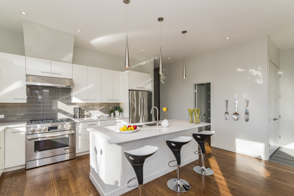White kitchen with stainless-steel appliances and black bar stools