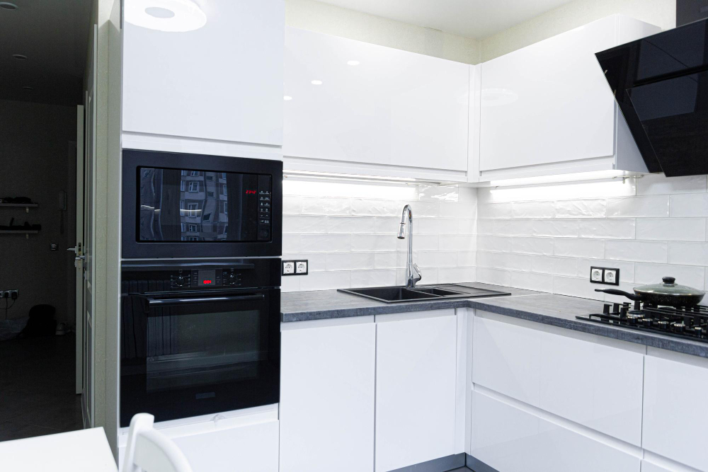 Compact white kitchen with black built-in oven, microwave and extractor hood