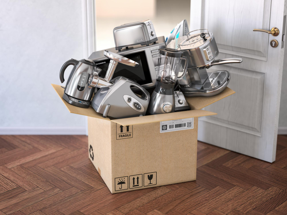 Small kitchen appliances gathered in a cardboard moving box